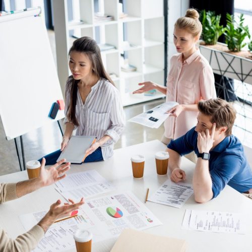 high-angle-view-of-group-of-young-business-people-discussing-new-project-on-small-business-meeting.jpg